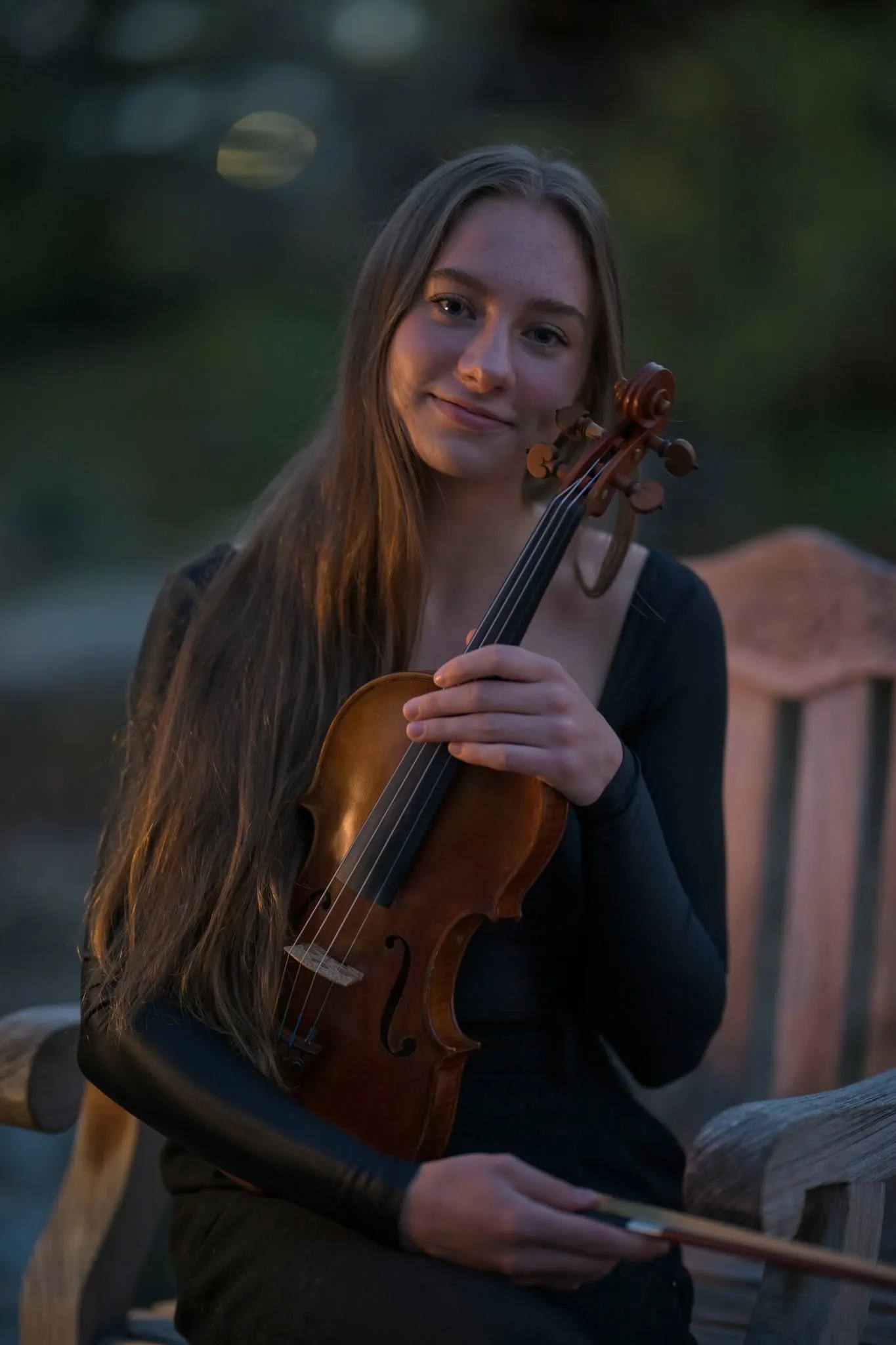 A young violinist holding her instrument in warm evening light