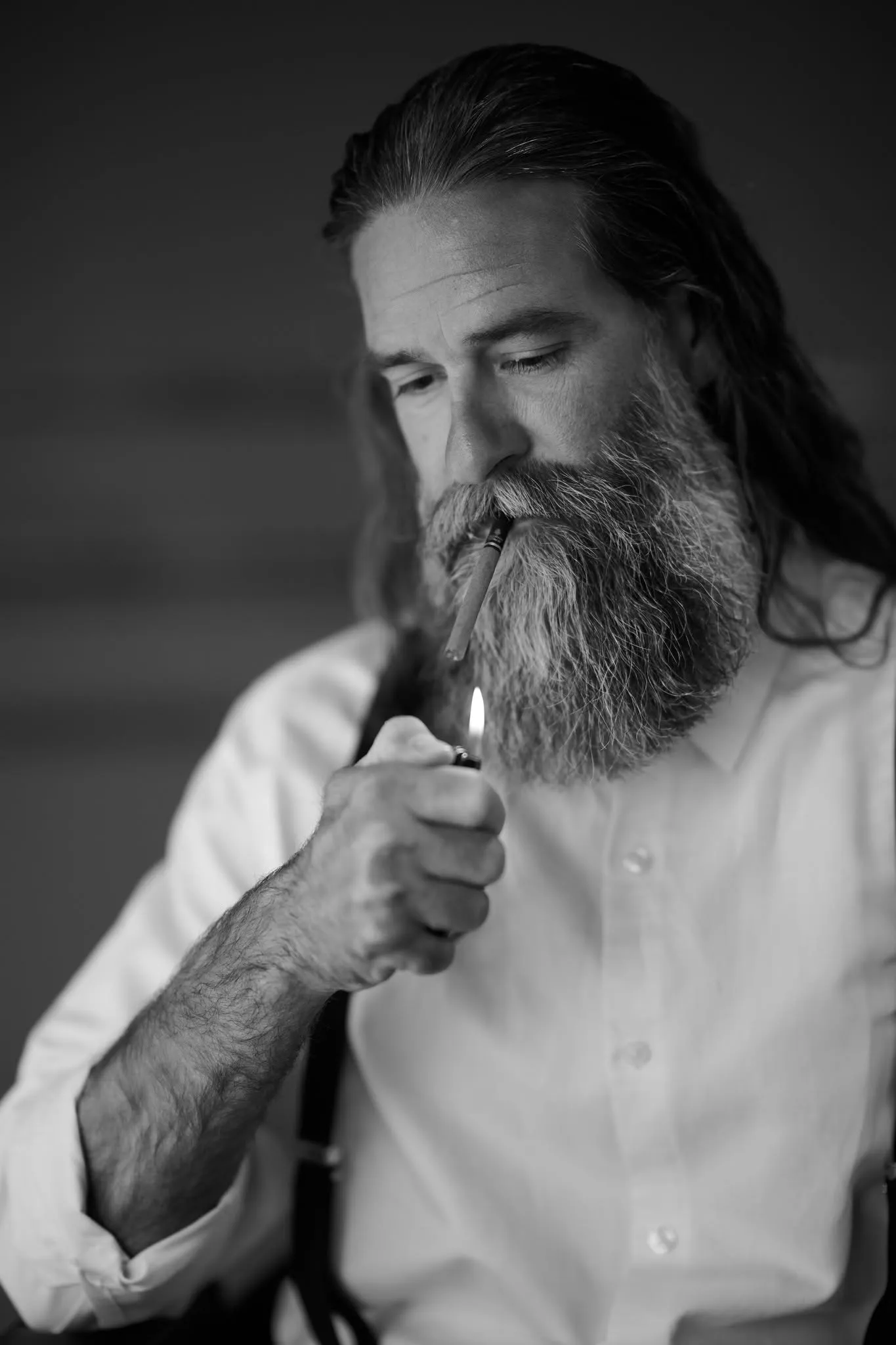 Black and white portrait of a bearded man in a white shirt and suspenders