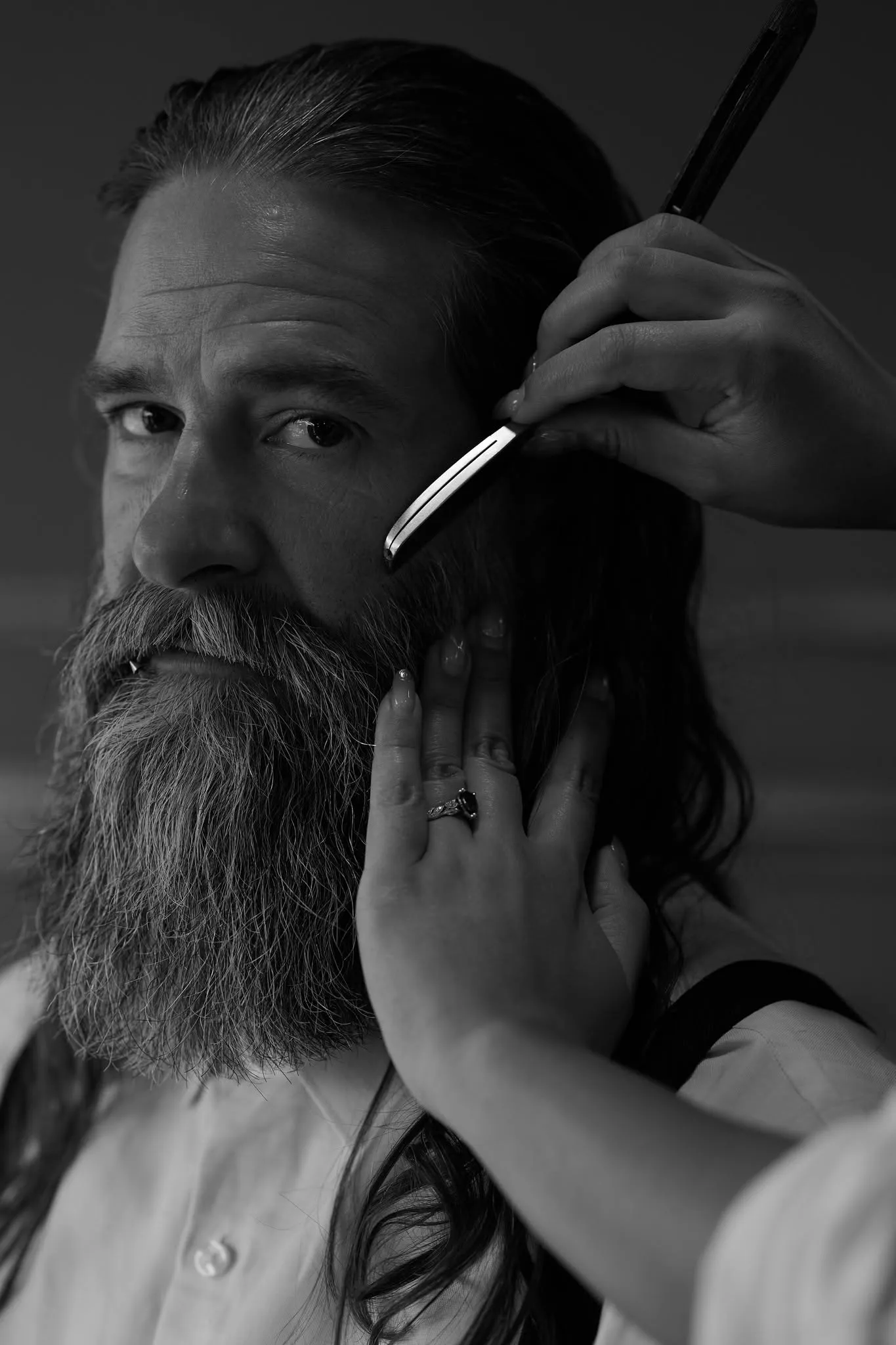A barber shaving a man with a straight razor
