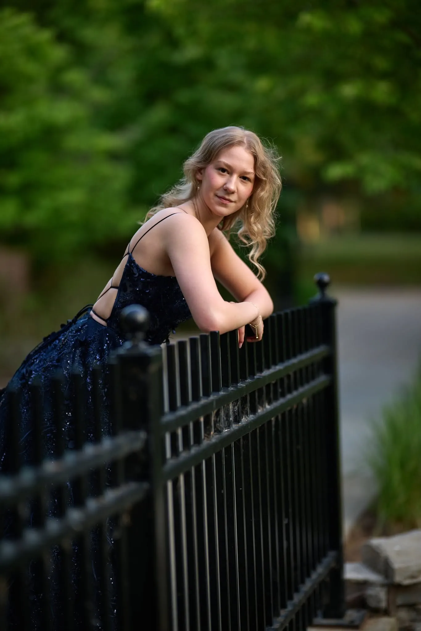 Woman in a navy gown beside an iron fence