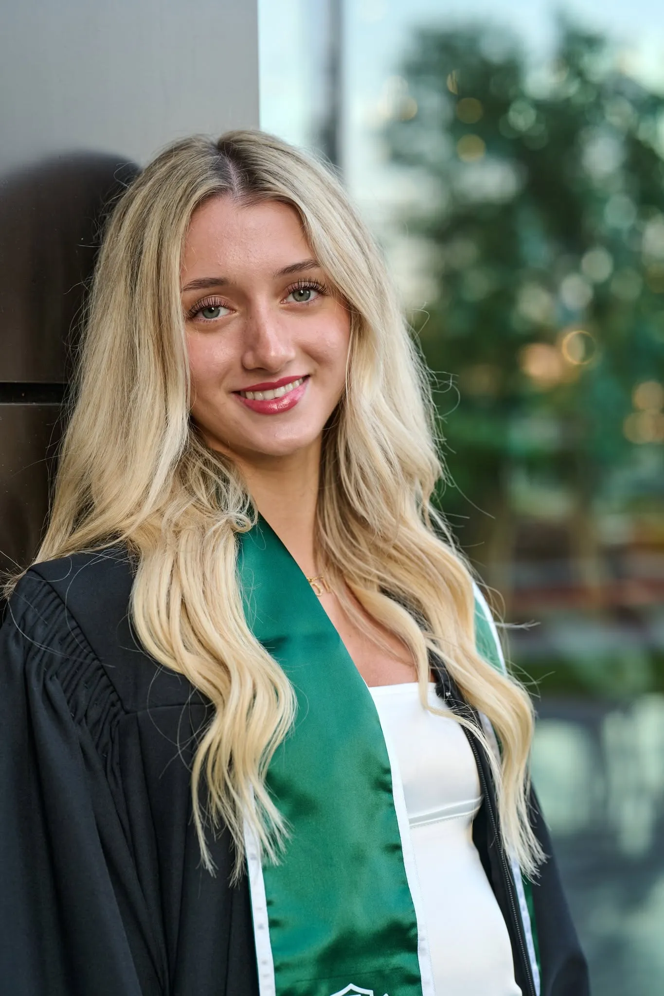 Graduate in cap and gown with a green stole