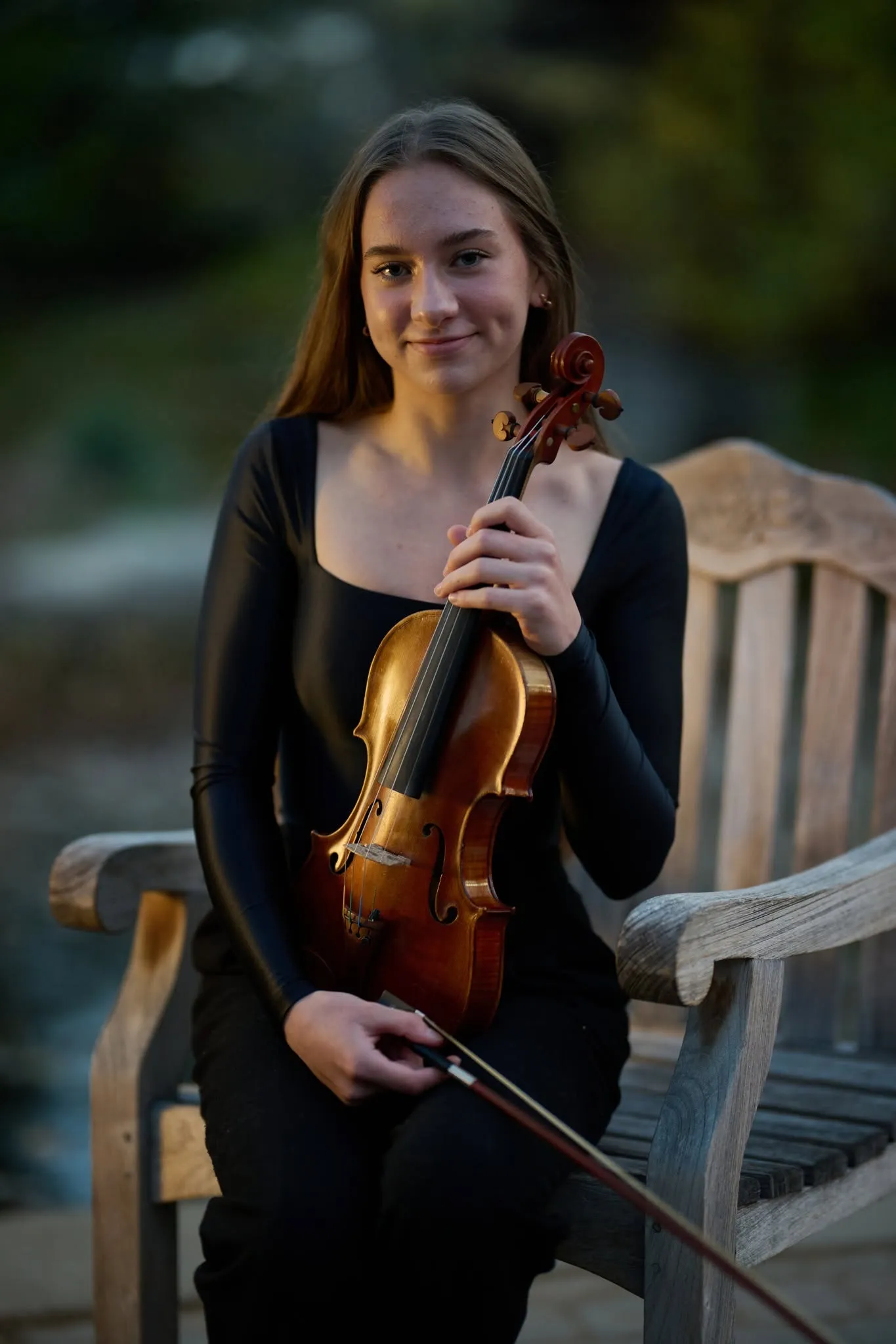 Violinist seated on a bench at dusk